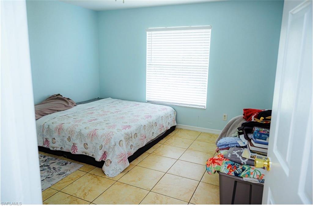 Room 2 featuring light blue walls, tiled flooring, a window with horizontal blinds, and a ceiling fan