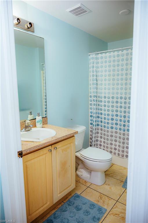 Bathroom featuring a single vanity with a countertop basin, a two-door wood-finish cabinet, and a wall-mounted mirror with a three-bulb light fixture