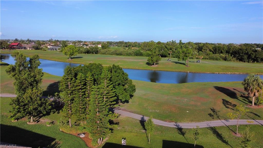 Expansive green space featuring a winding waterway, mature trees, and paved pathways