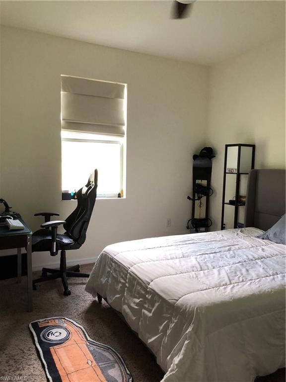 Bedroom featuring a single window with Roman shades, a ceiling fan, and carpeted flooring