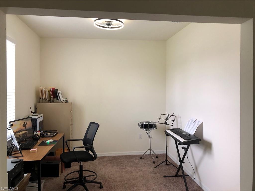 Carpeted interior room with neutral-toned walls, featuring a window with horizontal blinds and a ceiling-mounted light fixture