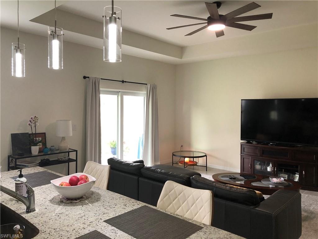 Open-concept living area featuring a tray ceiling, recessed lighting, and a contemporary ceiling fan