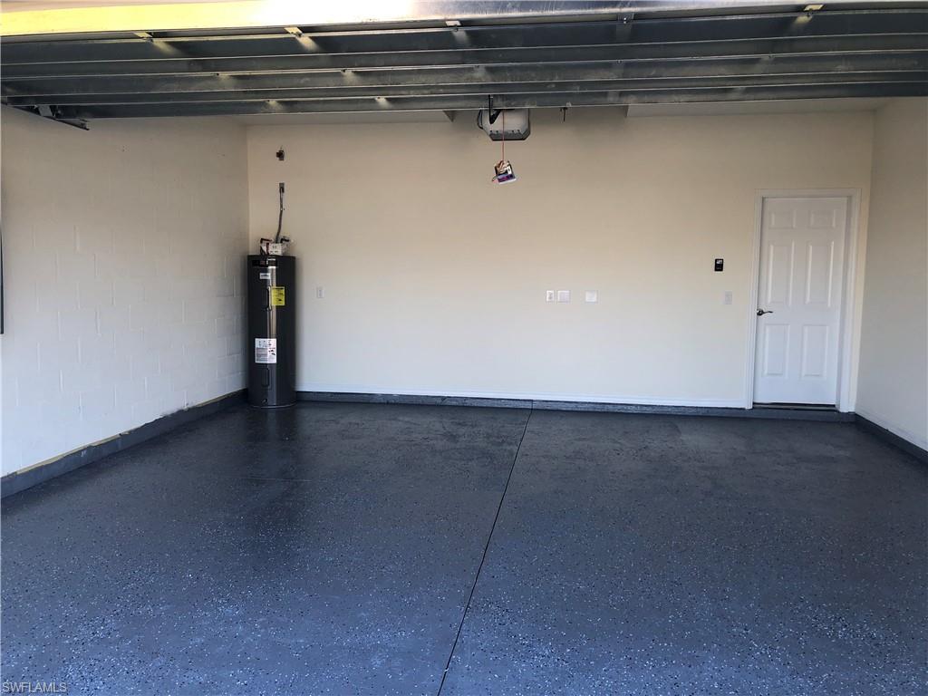 Spacious garage featuring an epoxy-coated concrete floor, painted walls, a water heater, and a paneled interior door