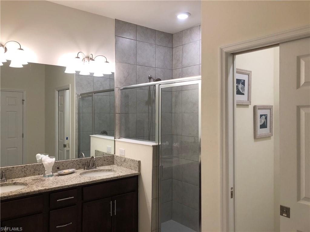 Spacious bathroom featuring a dual vanity with light-toned countertops, dark wood cabinetry, and chrome fixtures