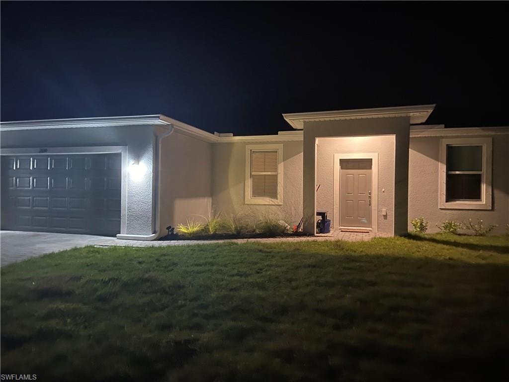 Contemporary stucco exterior with a gray panel garage door, covered entry, and front landscaping