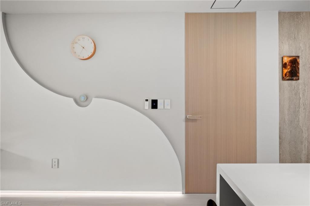 Modern interior wall featuring a light wood-finish door, a curved architectural detail, and an integrated lighting strip at the base