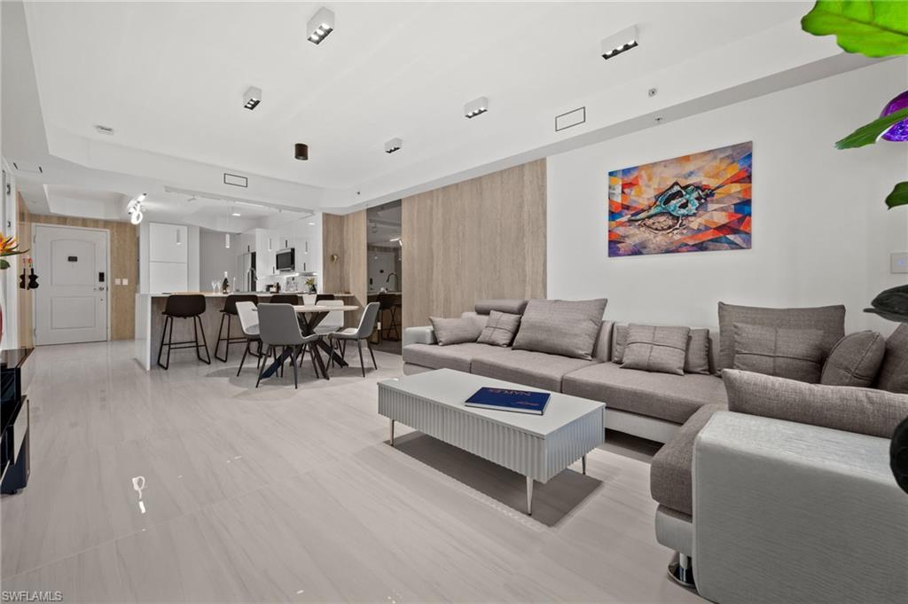 Open-concept living space featuring light-toned flooring, recessed lighting, a modern kitchen with a breakfast bar, and a dining area
