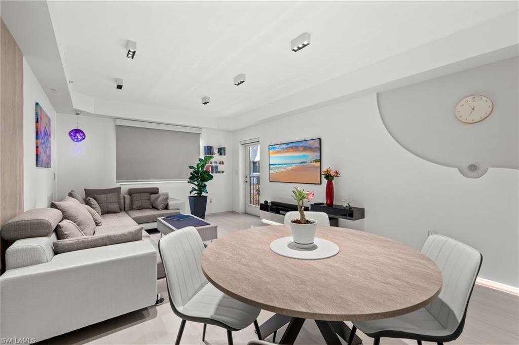 Open-concept living and dining area featuring light-toned flooring, recessed lighting, and a neutral color palette