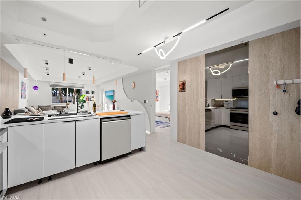 Modern kitchen featuring white flat-panel cabinetry, a stainless steel dishwasher, and a black sink with a wall-mounted faucet