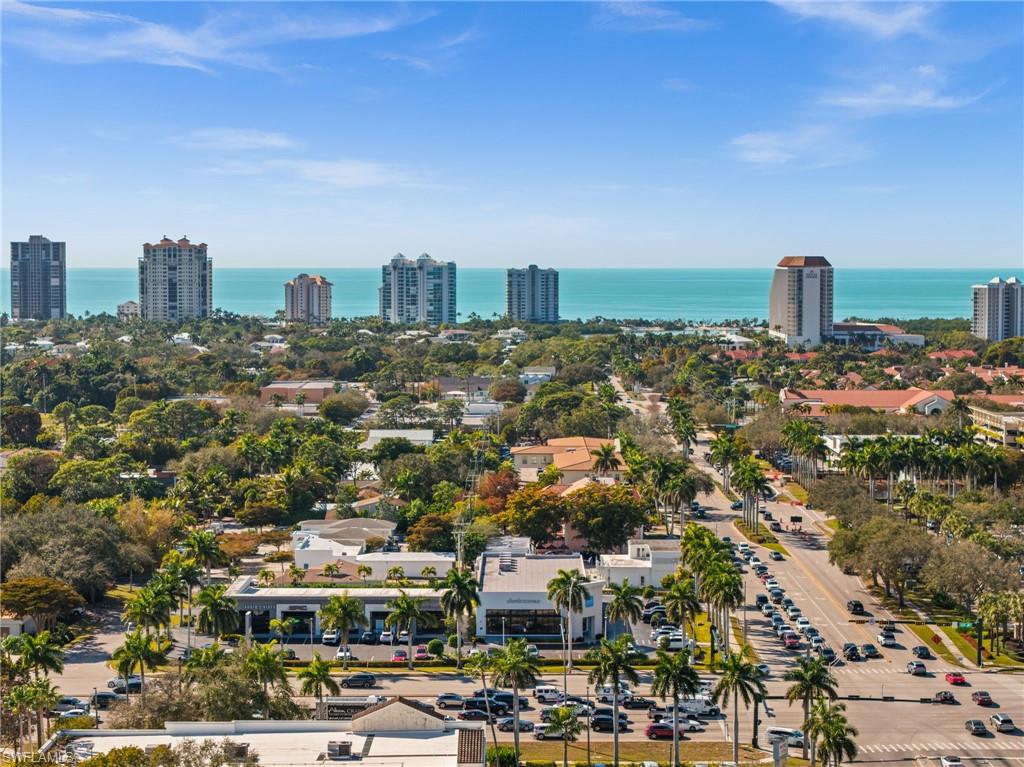 Aerial perspective showcasing the vibrant coastal area with prominent high-rise buildings, lush green landscaping, and the expansive turquoise ocean