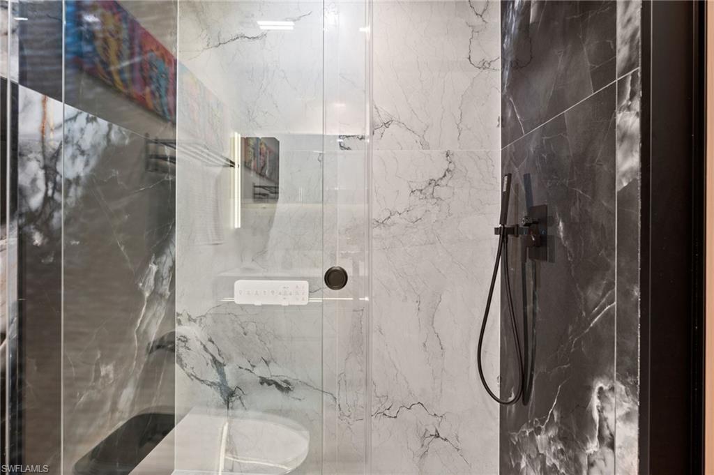 Modern shower enclosure featuring a glass panel, dark matte fixtures, and contrasting light and dark patterned wall tiles