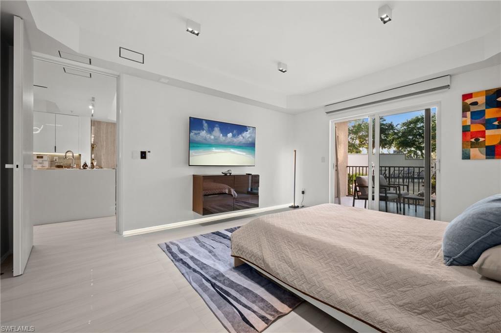 Open concept sleeping area featuring light wood-finish flooring, recessed lighting, and a sliding glass door to a private balcony