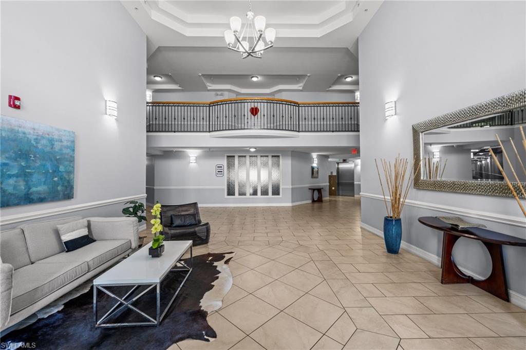 Two-story foyer featuring a contemporary chandelier, geometric tile flooring, tray ceilings, and a second-level balcony with metal balusters