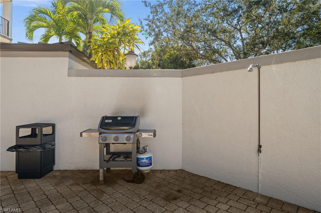 Private outdoor patio featuring textured concrete walls, paver flooring, and an integrated outdoor shower fixture