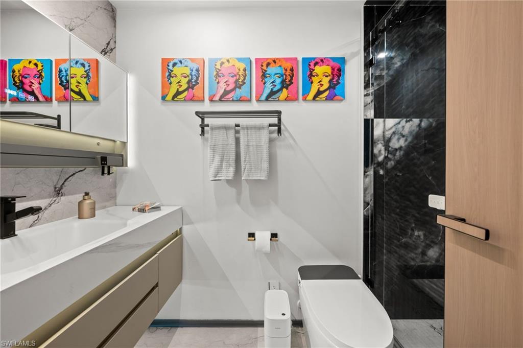 Contemporary bathroom featuring a floating vanity with an integrated sink, a matte black faucet, and a large illuminated mirror