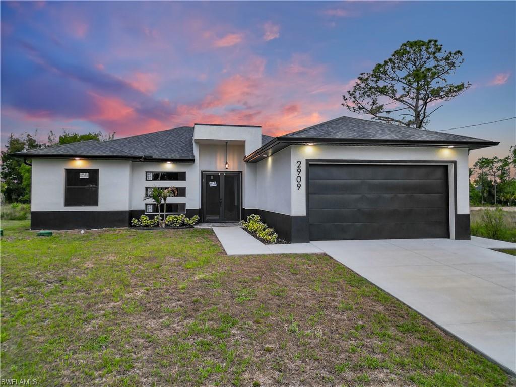 Contemporary single-story residence featuring a two-tone exterior, attached garage, covered entryway, and a concrete driveway