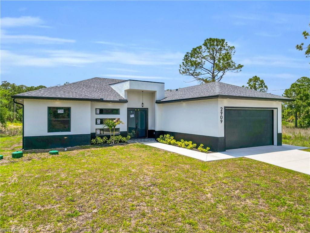 Contemporary exterior featuring a split-level roofline, dark-framed windows, and a two-tone stucco finish