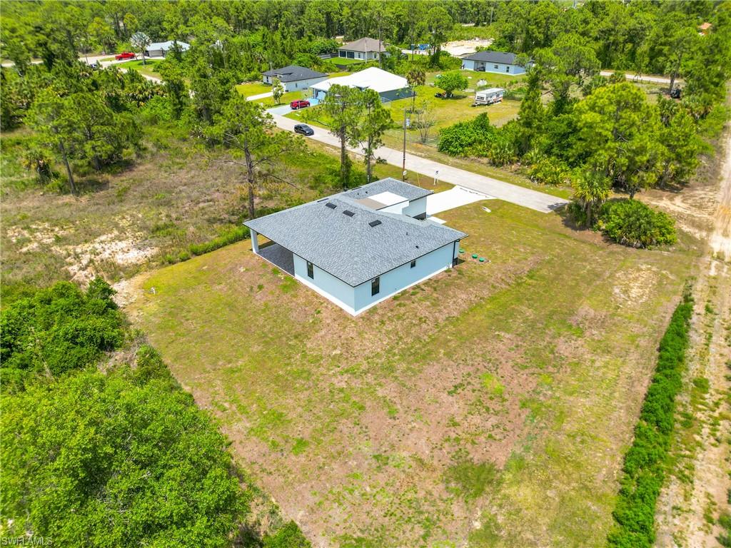 Newly constructed residence featuring a light blue exterior, a dark shingle roof, and a covered back patio