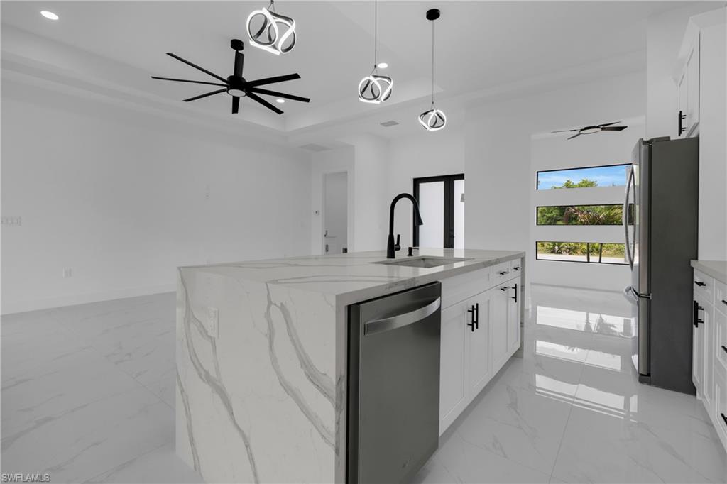 Kitchen island with waterfall-edge countertop, integrated sink with matte black faucet, and stainless steel dishwasher