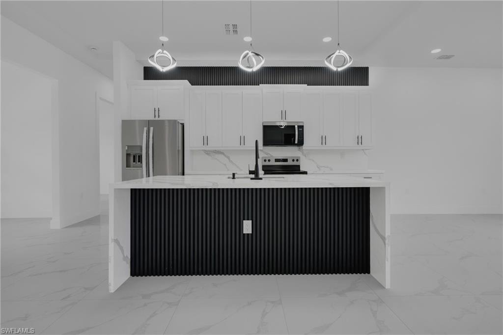 Modern kitchen featuring a waterfall island with a slatted black base, white cabinetry, integrated stainless steel appliances, and sleek pendant lighting