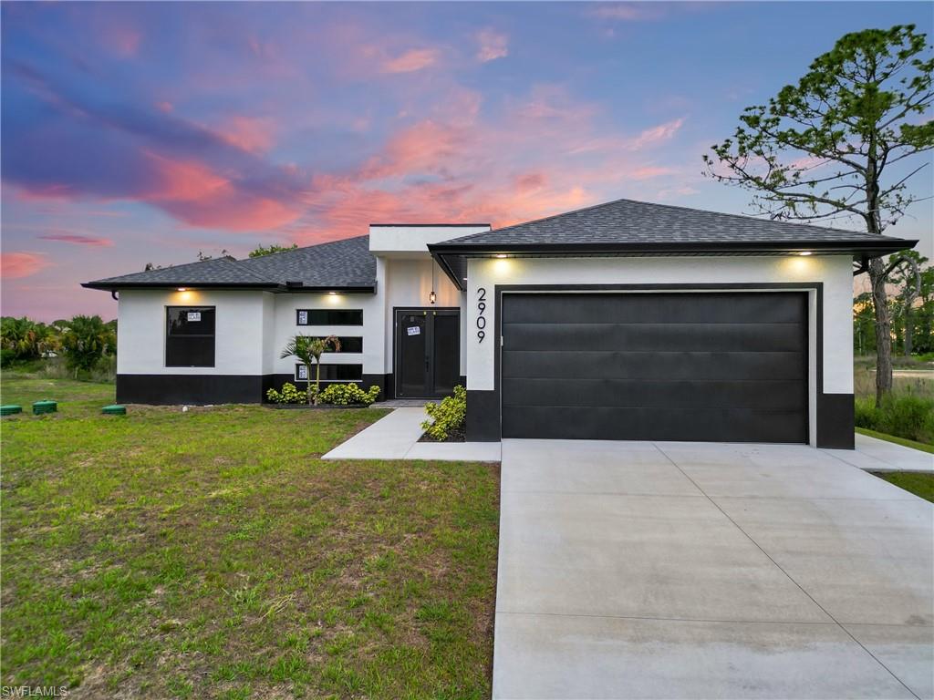 Contemporary exterior featuring white stucco with a black base, a dark asphalt shingle roof, and a two-car garage with a black door
