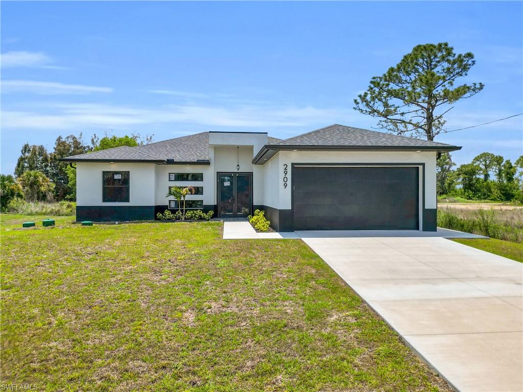 Contemporary stucco exterior with a dark asphalt shingle roof, integrated two-car garage, and a concrete driveway