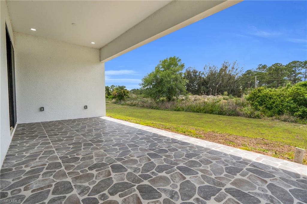 Covered patio featuring a mosaic stone-look tile floor, recessed lighting, and a stucco exterior wall