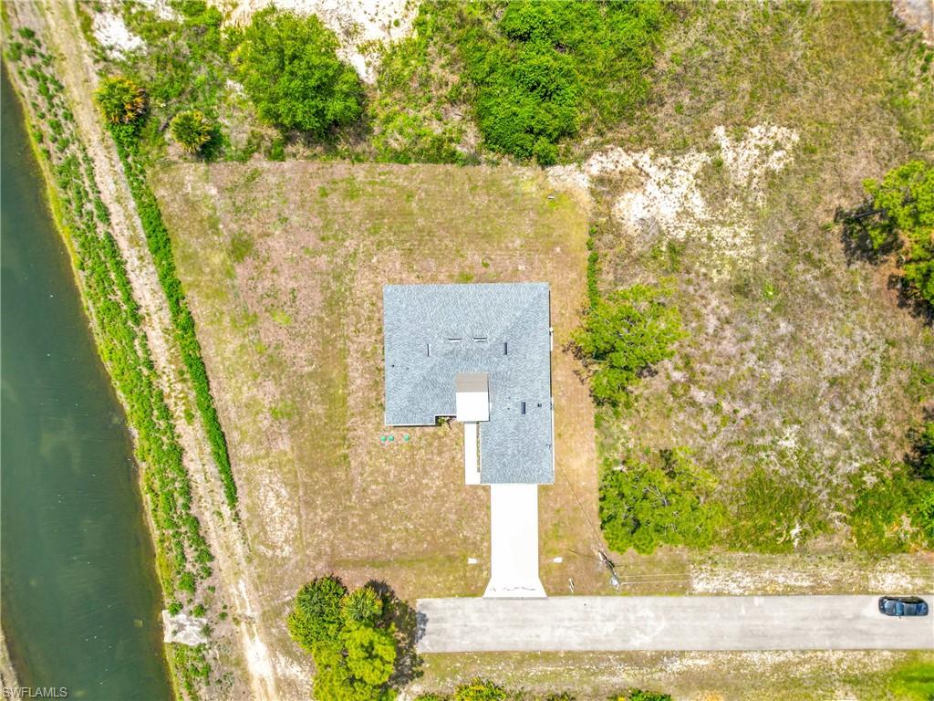 Aerial view showcasing a detached single-story residence with a gray shingle roof