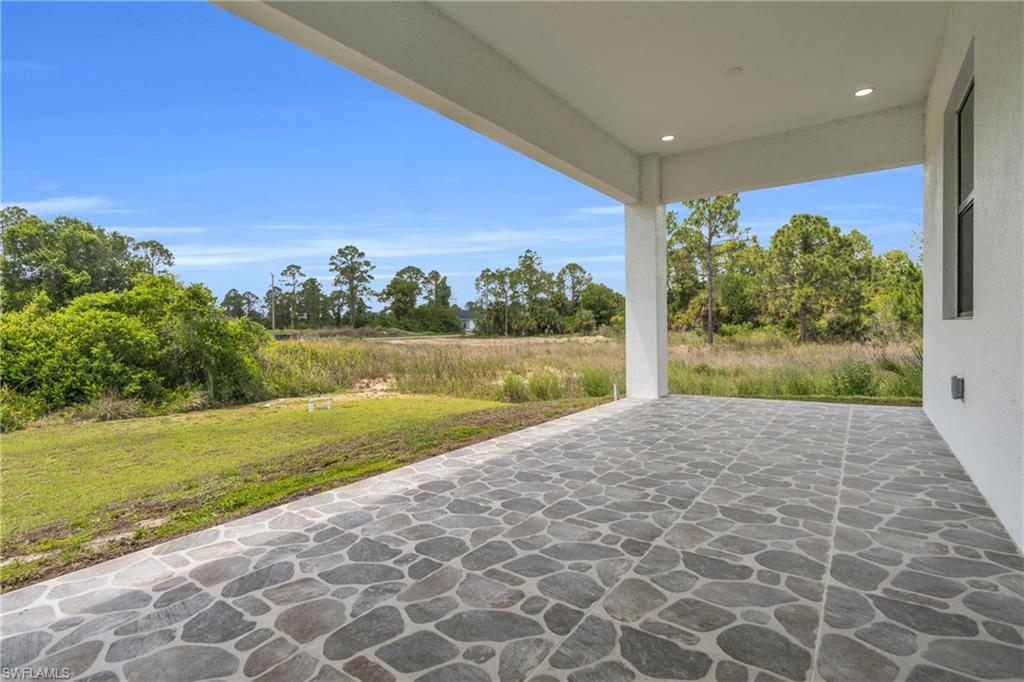 Expansive covered patio featuring a flagstone-patterned tile floor, recessed lighting, and a white stucco exterior wall