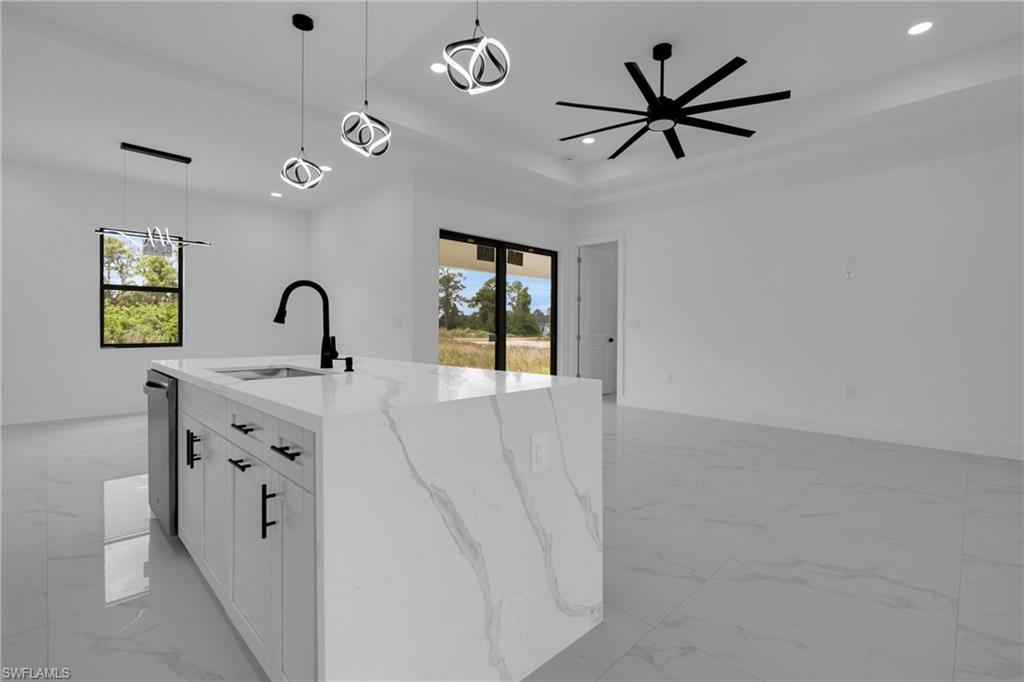 Kitchen island featuring a waterfall countertop with integrated sink and matte black faucet