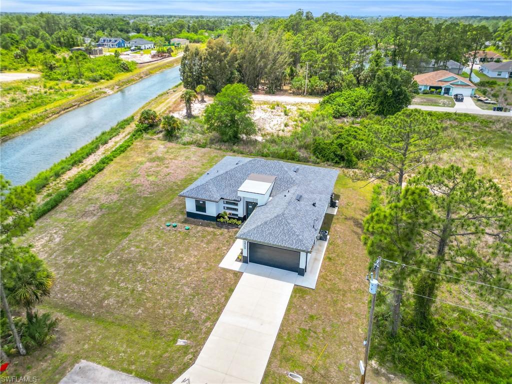 Contemporary residence with a dark shingle roof, attached garage, and a long concrete driveway