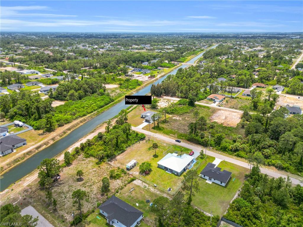 Canal-front property featuring a single-story residence with a light-colored roof and a paved driveway