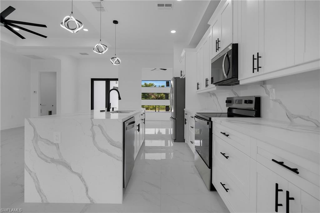 Kitchen featuring a waterfall-edge island, integrated sink with matte black faucet, and stainless steel appliances