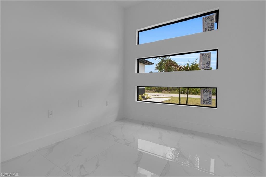 Interior space featuring three horizontal transom windows, white walls, white baseboards, and large format white tile flooring with subtle veining