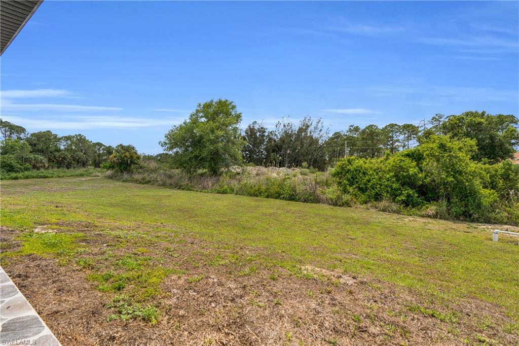 Expansive outdoor space featuring a large grassy area, mature trees, and natural landscaping