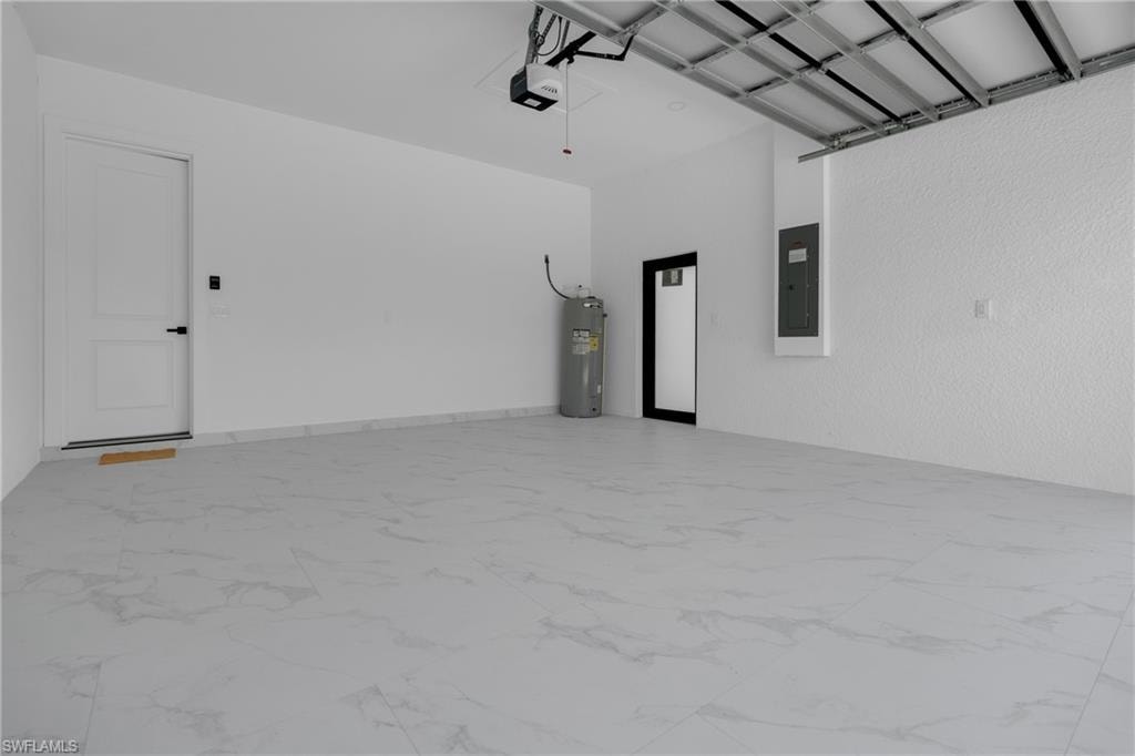 Spacious garage featuring large format tile flooring, white walls, and a finished ceiling with exposed support beams
