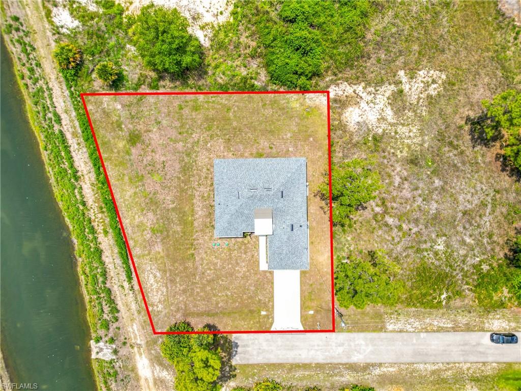 Aerial perspective showcasing the property's perimeter, a single-story residence, and a paved driveway