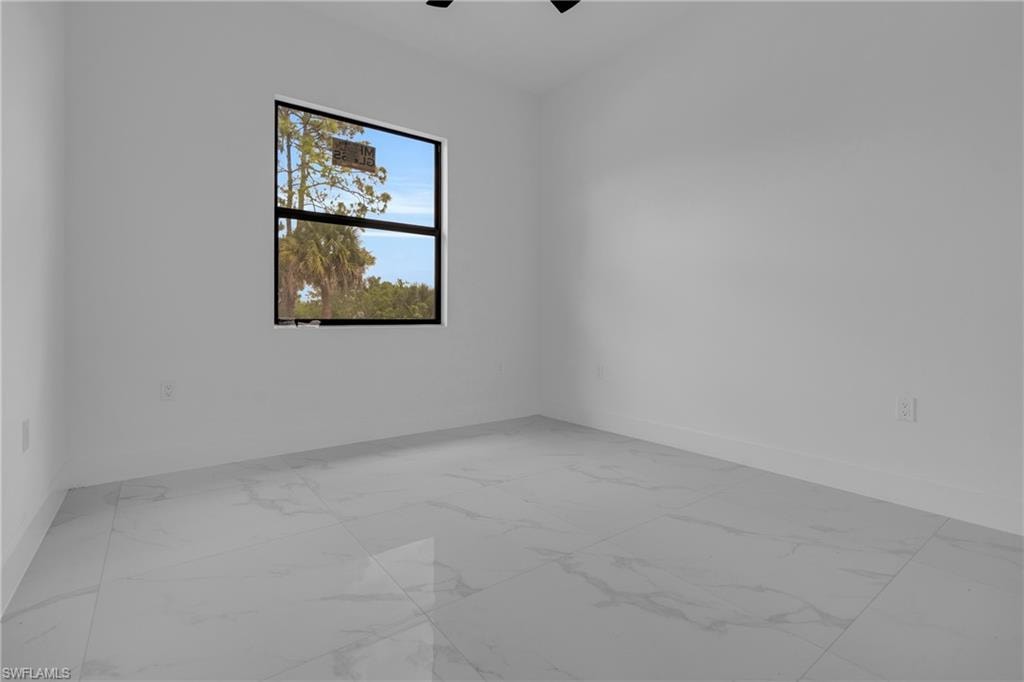 Spacious room featuring large format tile flooring, white baseboards, and a large window with black framing