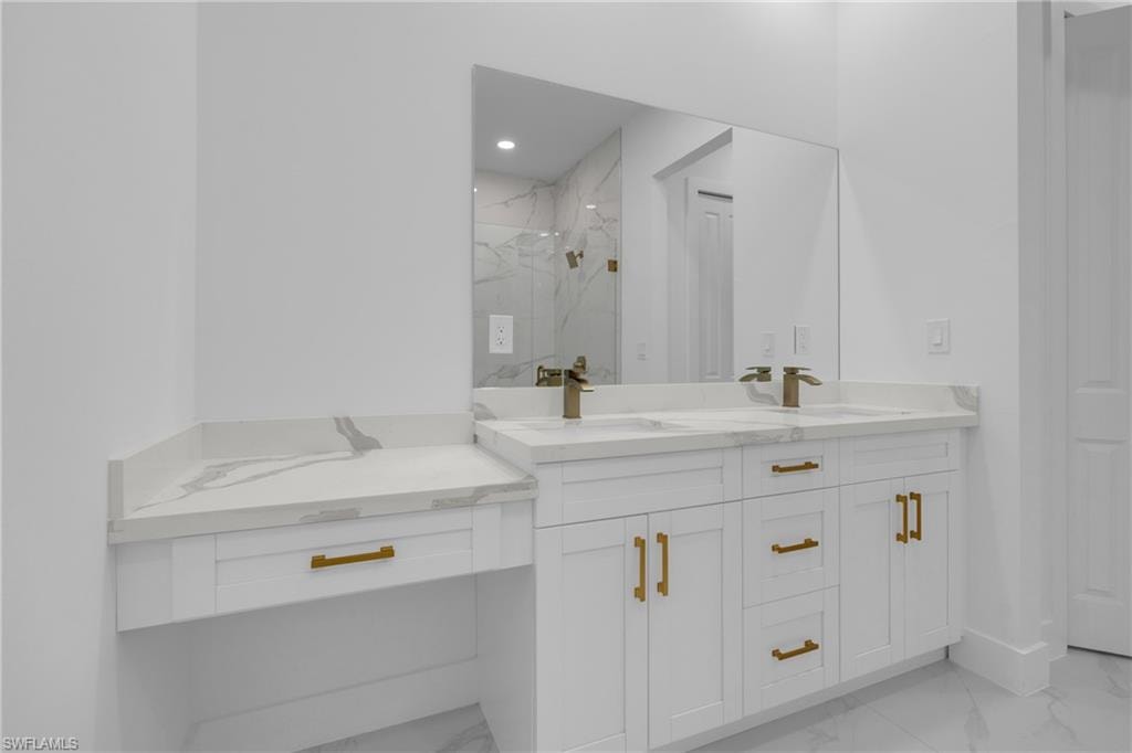 Dual vanity with integrated sinks, quartz countertops, bronze-finish faucets, white shaker cabinetry, and a dedicated vanity seating area