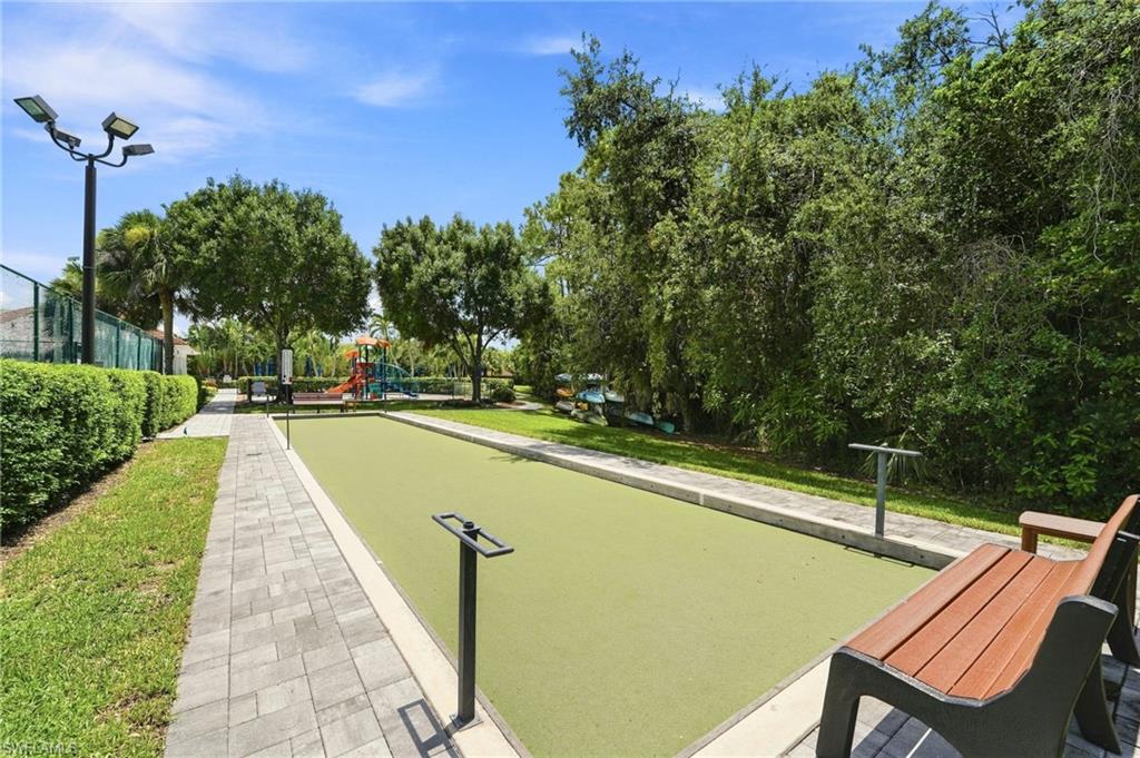 Bocce ball court with paver stone walkway, adjacent to lush landscaping