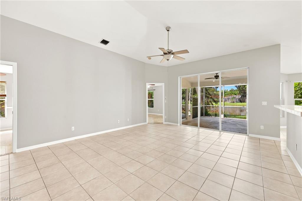 Expansive living area featuring vaulted ceilings, light tile flooring, and sliding glass doors to the screened patio