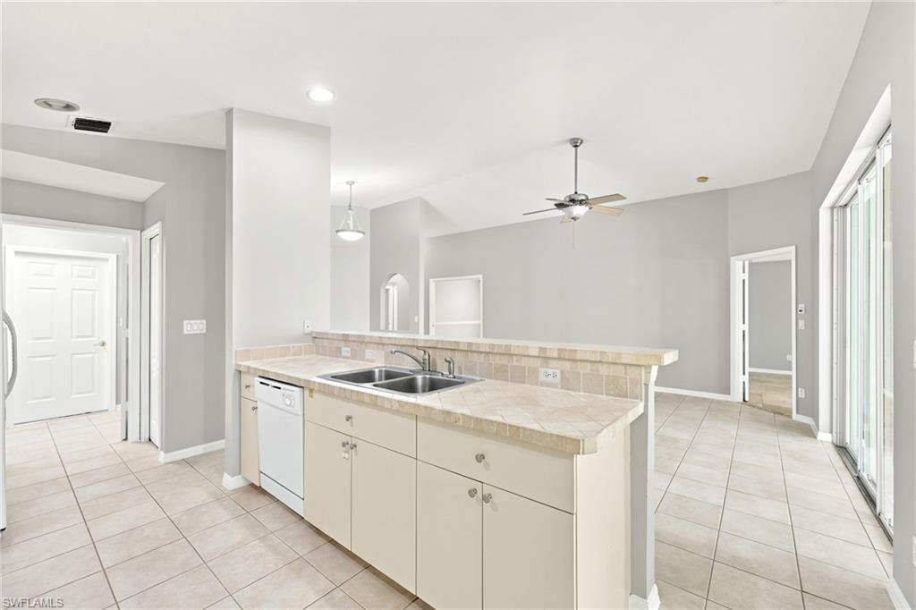 Open-concept kitchen with a breakfast bar, dual stainless steel sinks, and tile flooring