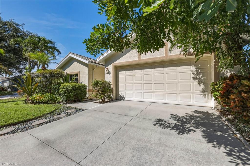 Exterior featuring a two-car panel garage door, concrete driveway, and stucco siding