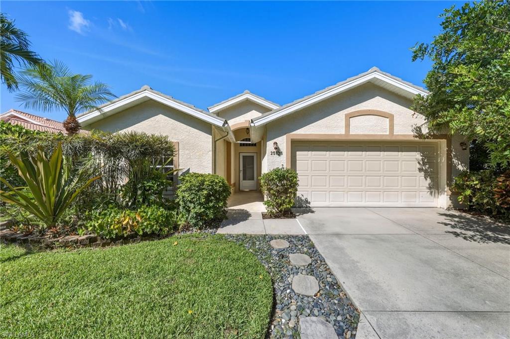 Stucco exterior residence with an arched entry, an integrated two-car garage, and mature landscaping