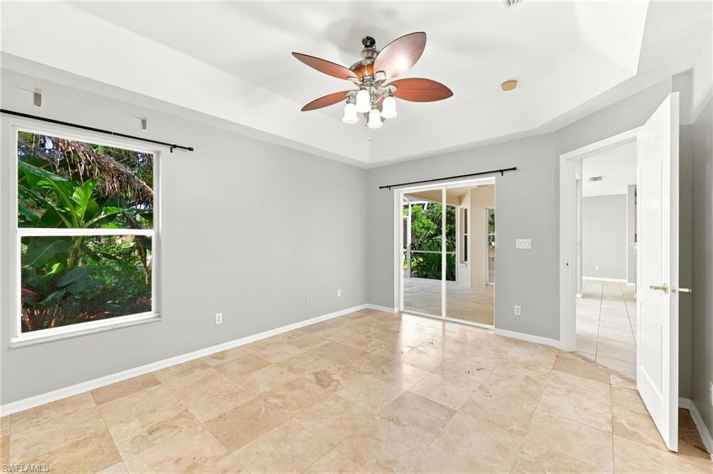 Spacious room featuring tile flooring, a tray ceiling with a ceiling fan, and direct access to an enclosed patio through sliding glass doors