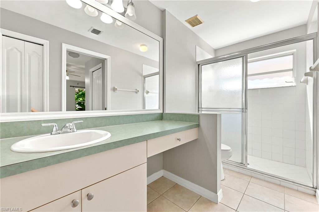 Bathroom vanity featuring an oval undermount sink with a chrome faucet, sage green countertop, and cream-colored cabinetry