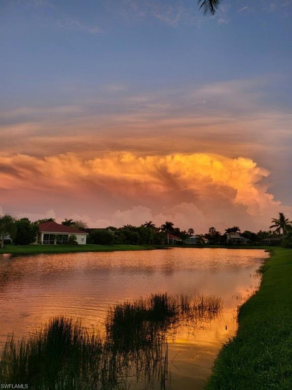 Waterfront property featuring a serene lake with natural vegetation, framed by a vibrant sunset sky