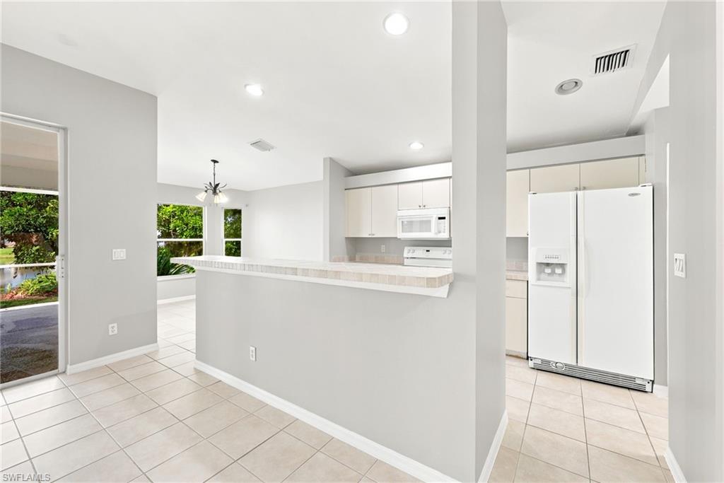 Open-concept kitchen and living area featuring a breakfast bar, white cabinetry, and a suite of white appliances