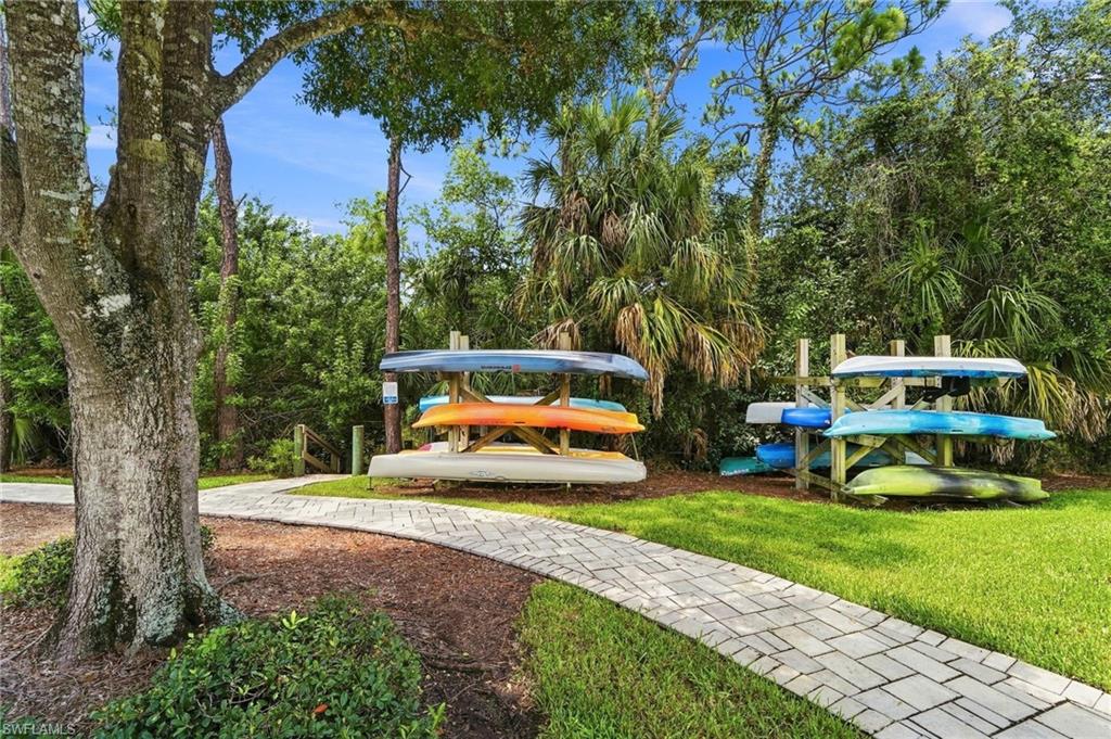 Expansive outdoor living space showcasing mature landscaping with towering oak and palm trees, manicured lawn, and brick paver walkway