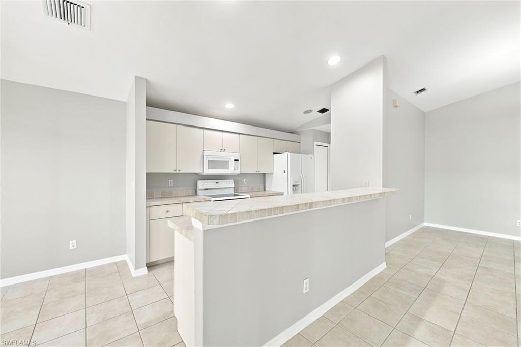 Kitchen featuring white cabinetry, a built-in microwave, and a white refrigerator